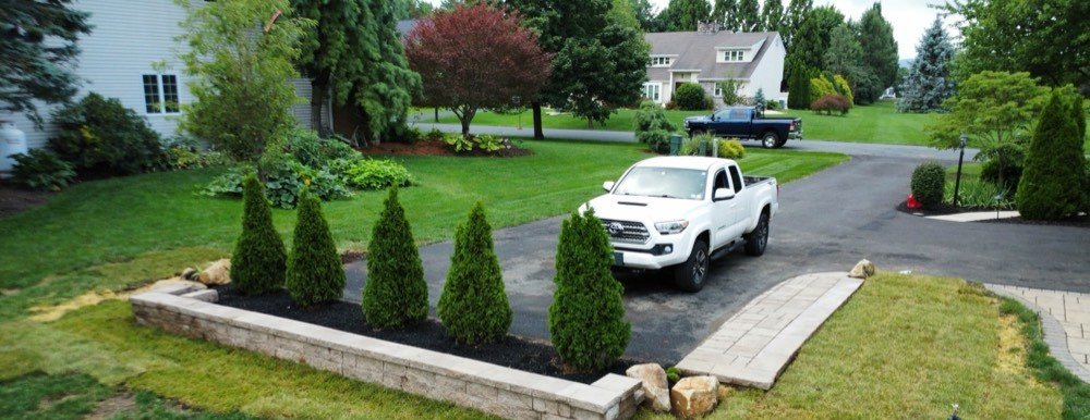 Stone retaining wall and paver walkway installed by Bechtel's Landscaping alongside a driveway