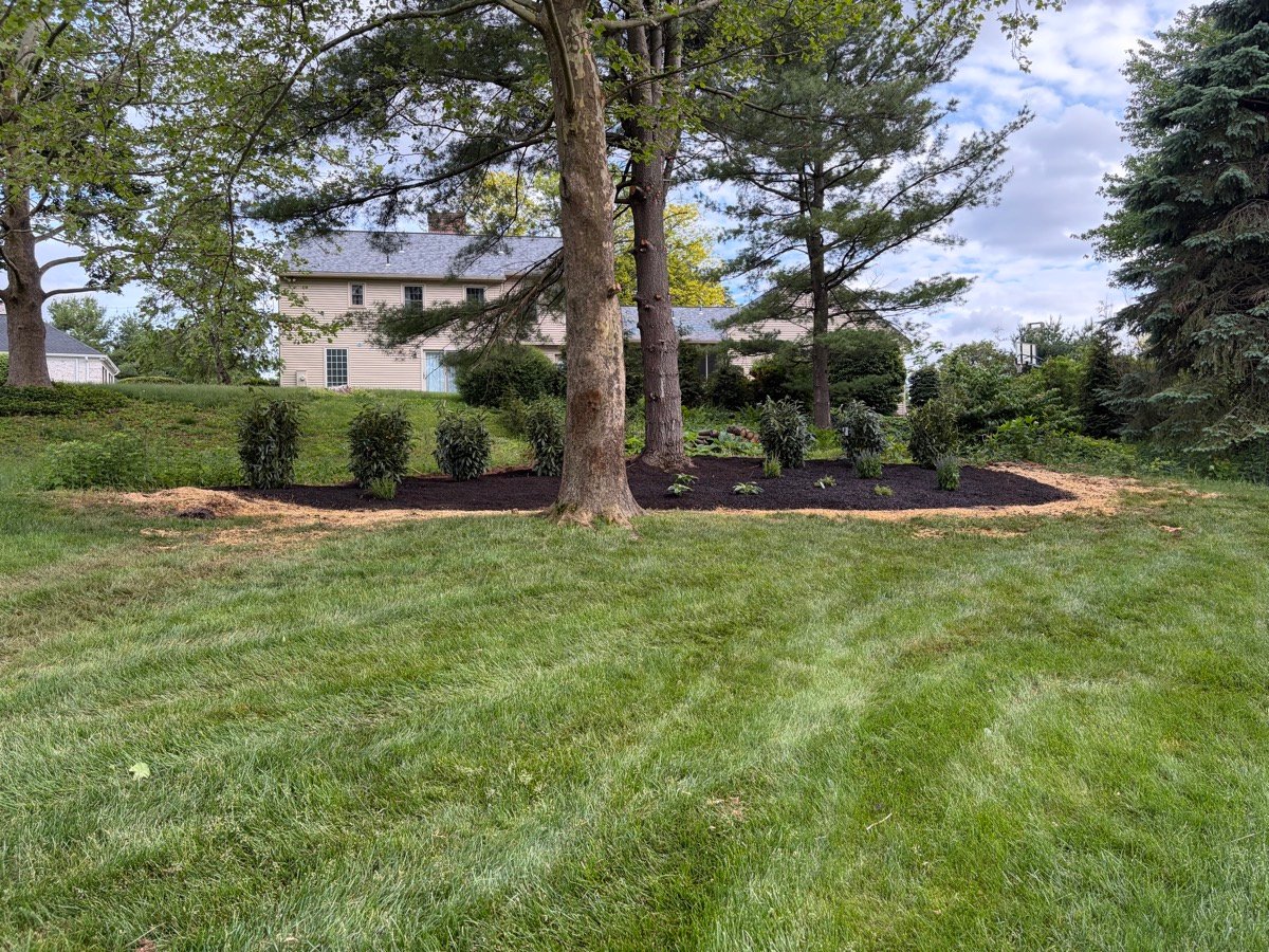 Bechtel's Landscaping crew maintaining a large property's stone wall border and lawn edge