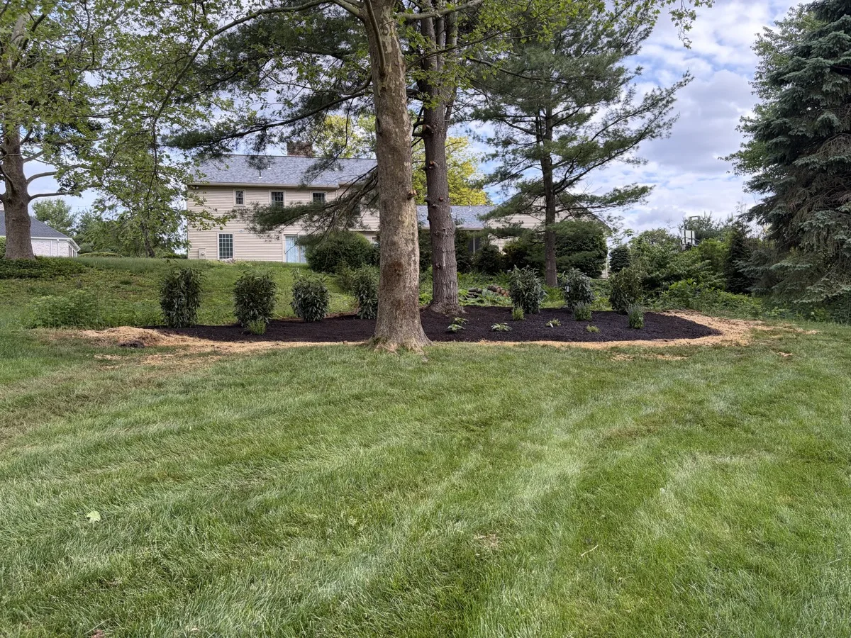 Bechtel's Landscaping crew maintaining a large property's stone wall border and lawn edge